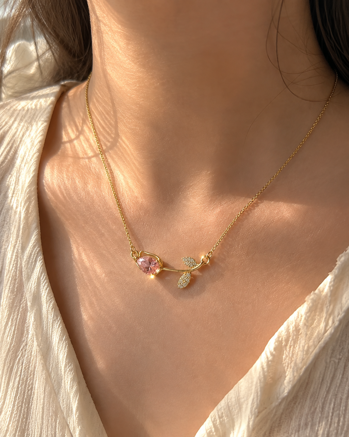 Delicate pink gemstone necklace for women featuring a polished gold-tone chain, pink teardrop stone and crystal leaf detail
