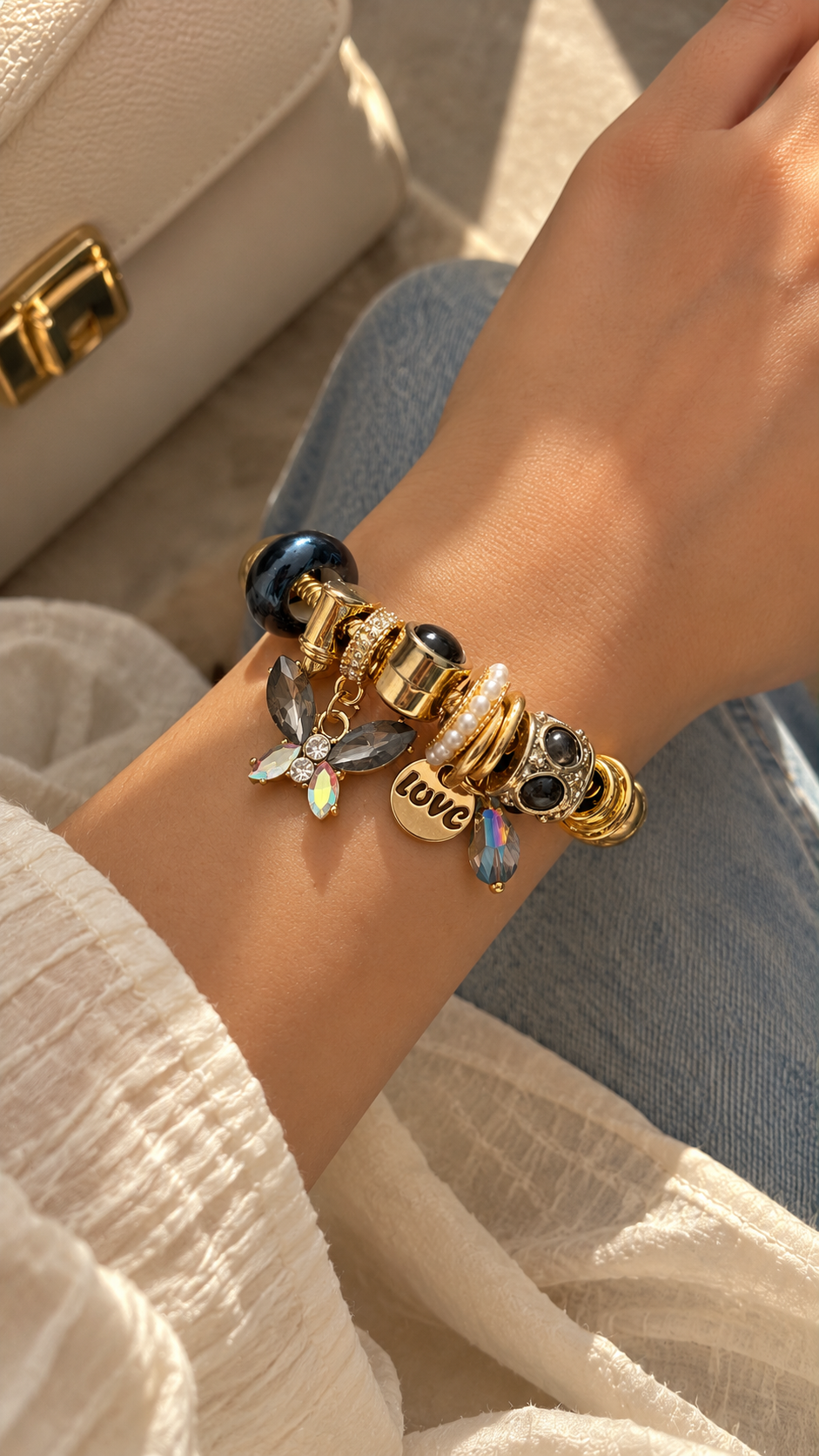 Detailed view of Ashaarya Midnight Love charm bracelet with decorative crystal charms, pearl accents and anti-tarnish charms in a gold-tone finish.