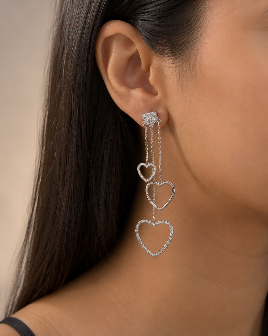Silver heart-shaped earrings worn by a person with a neutral background. 925 sterling silver earrings, sterling silver heart studs, silver heart earrings, 925 silver earrings for women, heart stud earrings, cubic zirconia earrings, hypoallergenic earrings, everyday silver jewellery, sterling silver studs, dainty silver earrings, silver jewellery India, Ashaarya