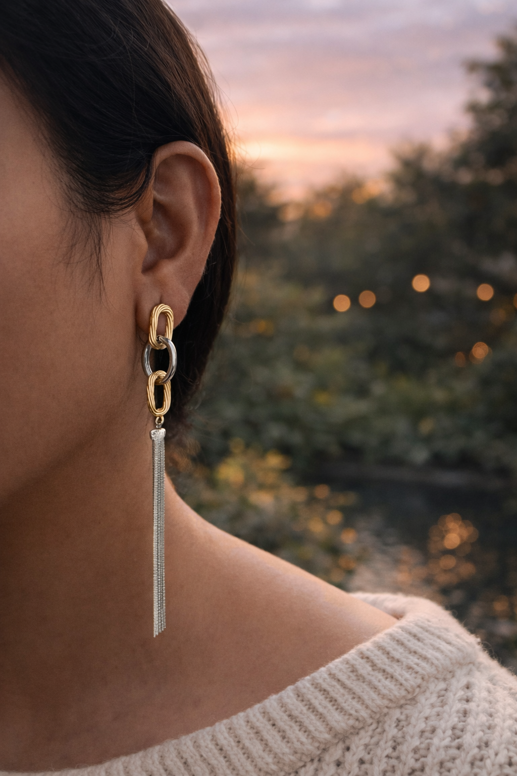 Anti-Tarnish, Ashaarya, Ashaarya Jewels, Ashaarya Jewellery, Close-up of a person wearing gold earrings with tassels against a blurred natural background.