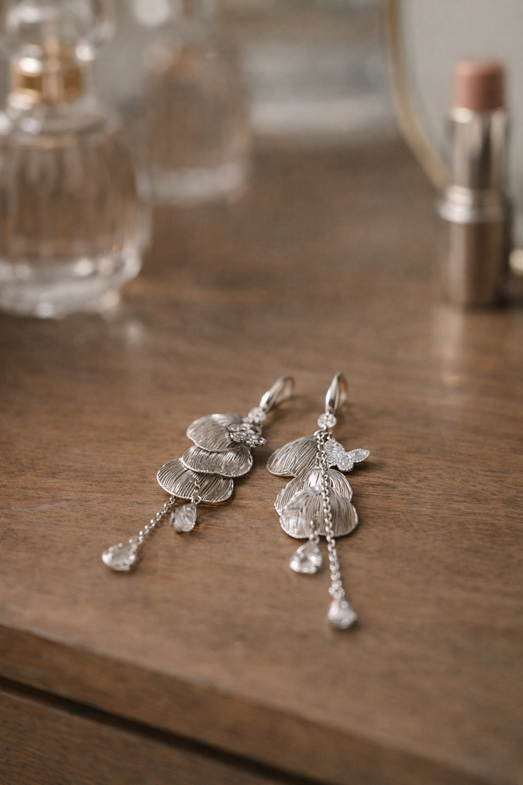 Anti-Tarnish, Ashaarya, Ashaarya Jewels, Ashaarya Jewellery, Silver earrings on a wooden surface with blurred perfume bottles in the background