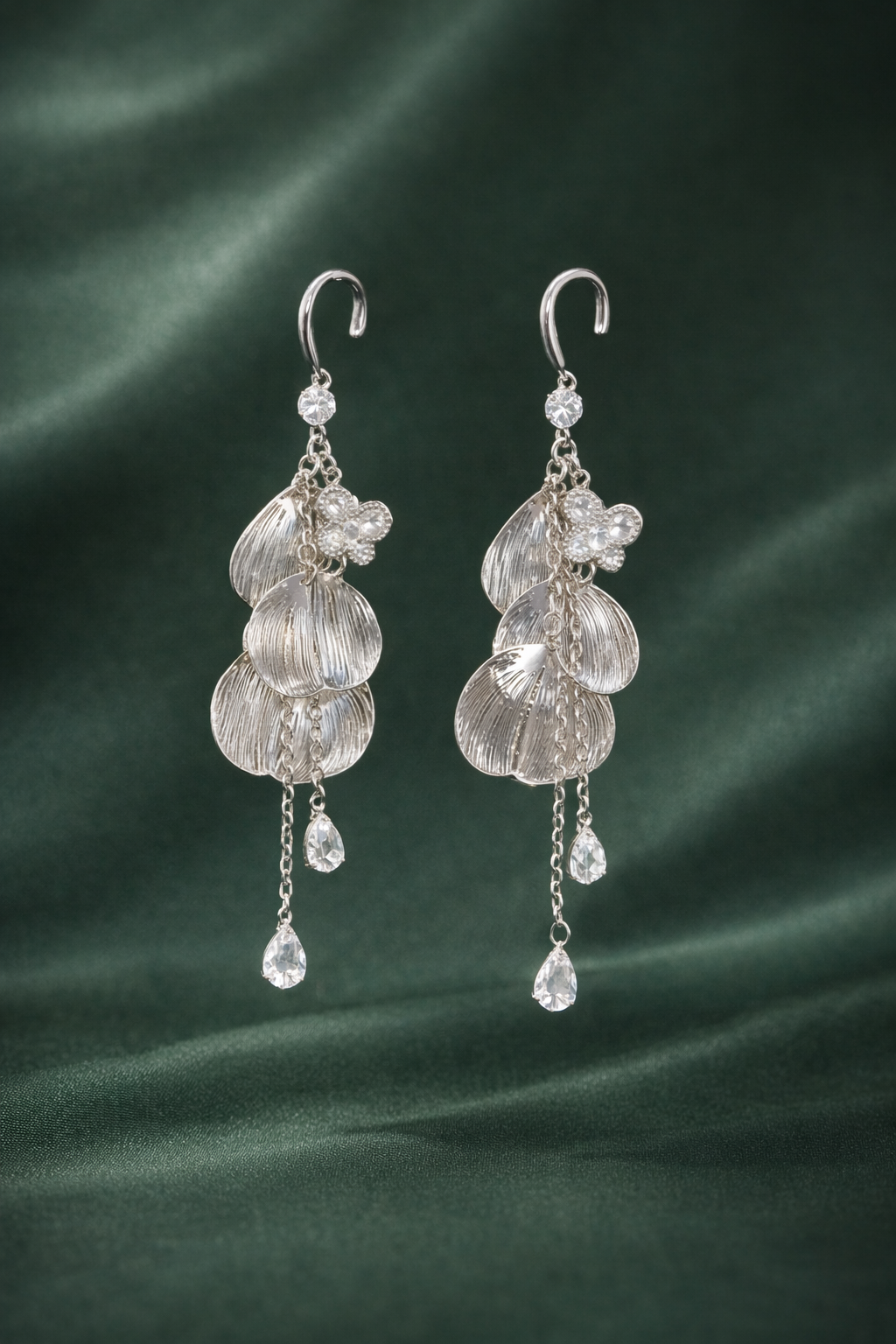 Anti-Tarnish, Ashaarya, Ashaarya Jewels, Ashaarya Jewellery,Pair of silver earrings with clear gemstones on a green fabric background