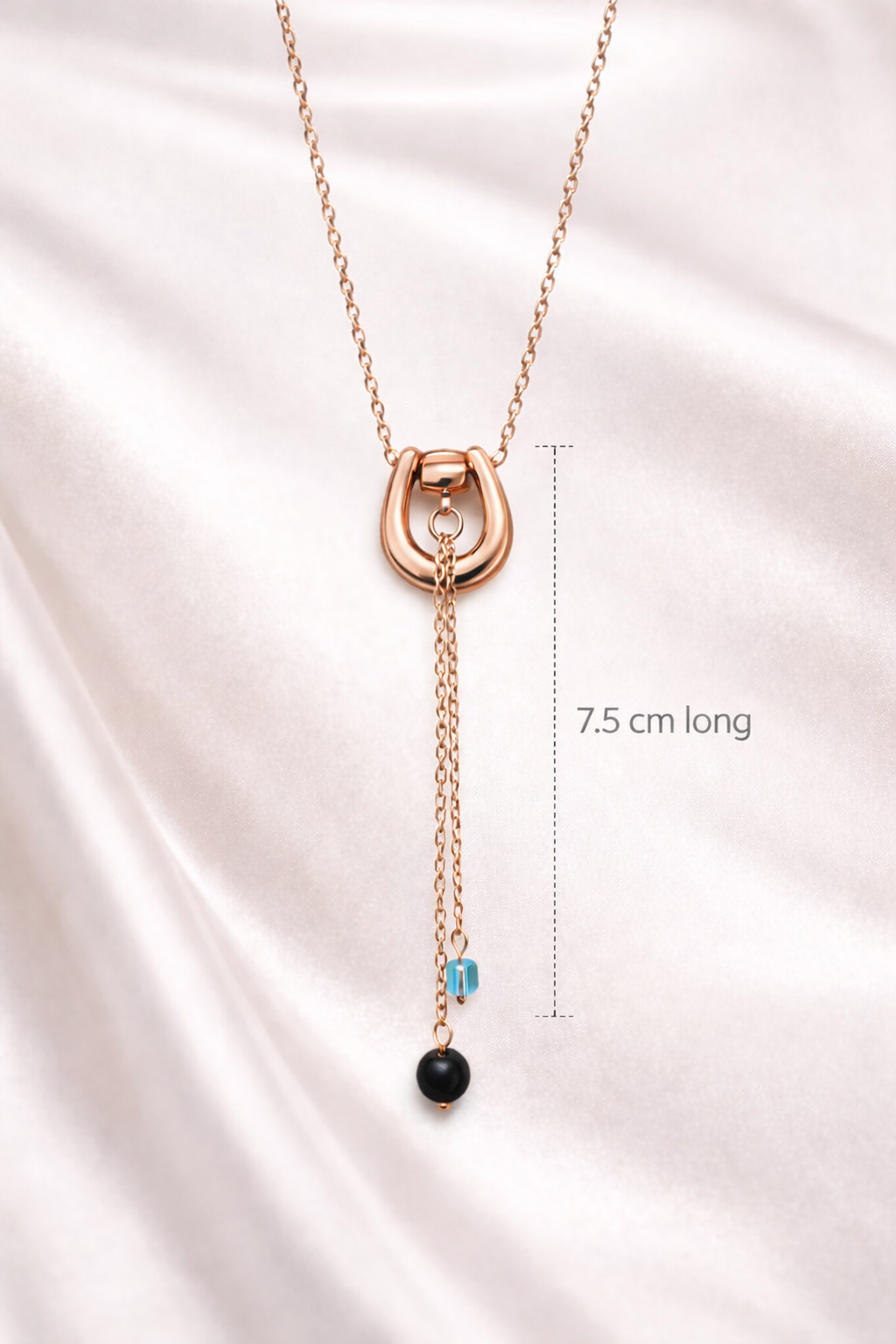 Rose gold necklace with pendant on a satin background, showing length measurement.