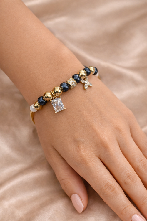 Anti-tarnish comfort jewellery charm bracelet for women with American diamond charms, gold tone beads and black stone beads – Ashaarya demi-fine charm bracelet close-up showing emerald cut stone charm and floral diamond charm