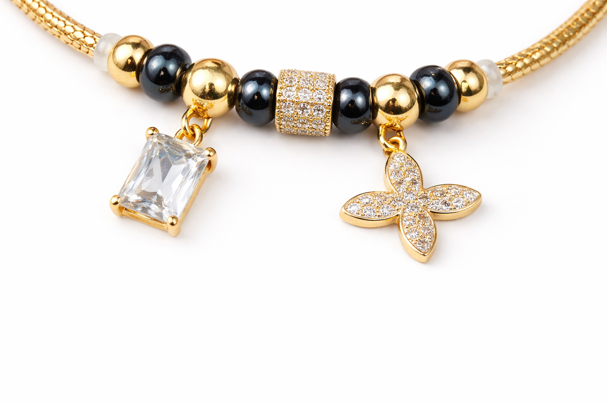 Anti-tarnish comfort jewellery charm bracelet for women with American diamond charms, gold tone beads and black stone beads – Ashaarya demi-fine charm bracelet close-up showing emerald cut stone charm and floral diamond charm