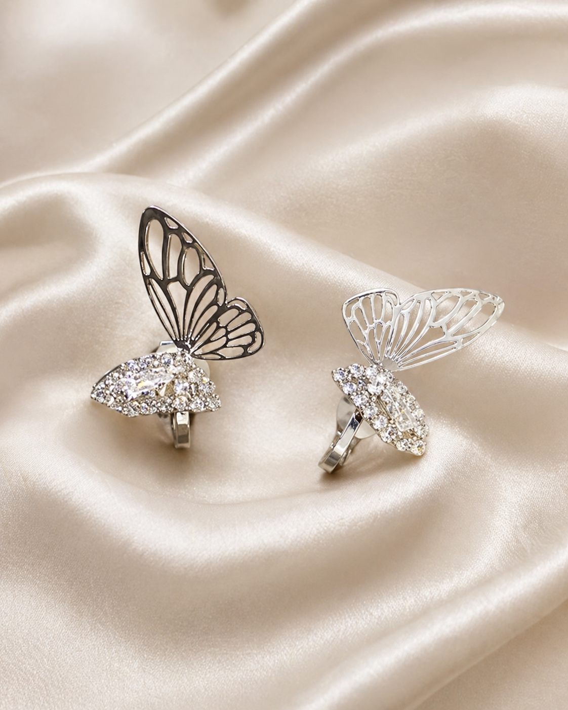 Anti-tarnish dangling earrings for women with wing-inspired design, lightweight comfort jewellery by Ashaarya. Butterfly-shaped silver rings with gemstones on a satin surface