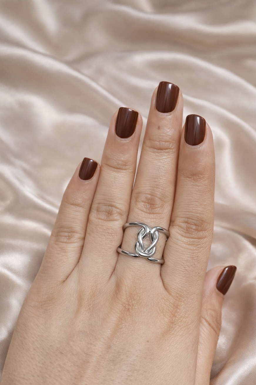 Anti-tarnish gold and silver duo ring stack worn on hand — adjustable comfort jewellery featuring twisted band and knot design, band rings for women, statement rings for women. Hand wearing a silver ring with a heart design on a satin background