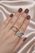 Anti-tarnish gold and silver duo ring stack worn on hand — adjustable comfort jewellery featuring twisted band and knot design, band rings for women, statement rings for women. Hand with brown nail polish wearing two rings on a satin background