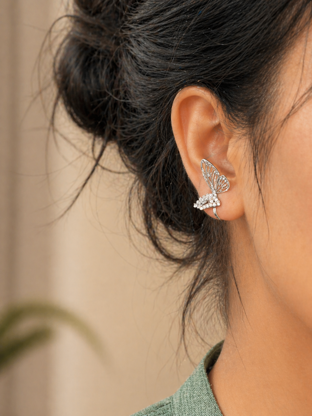Macro shot of anti-tarnish earrings showing fine zircon detailing and wing structure, comfort jewellery by Ashaarya. Close-up of a person wearing a silver earring with a blurred background
