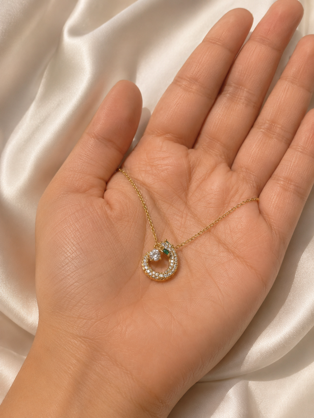 Close-up of the Emerald Serpent Necklace pendant featuring sparkling American diamonds and a green accent