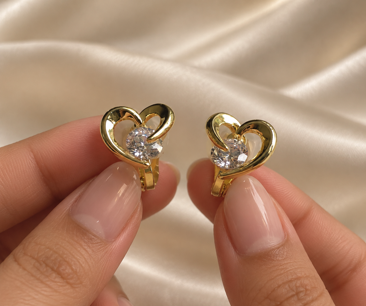Anti-tarnish gold heart clip-on earrings featuring a polished open-heart design and brilliant clear crystal, designed for elegant everyday wear