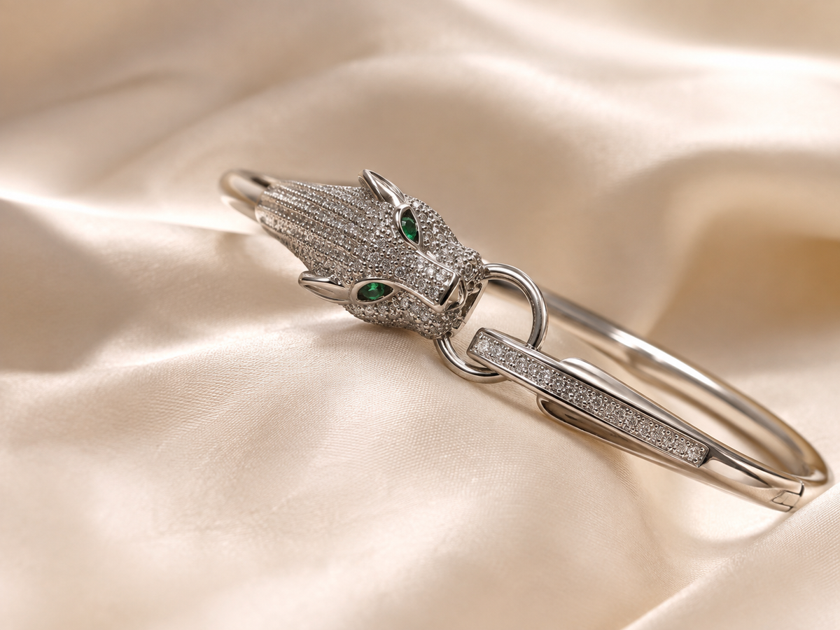 Anti-tarnish statement panther bracelet with a silver-tone sculptural design, crystal detailing and distinctive green gemstone eyes