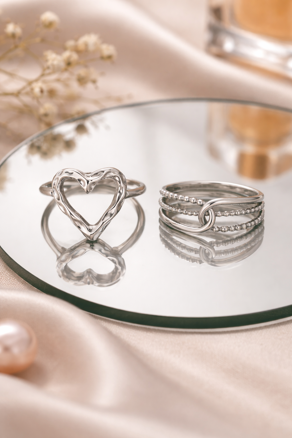 Anti-Tarnish, Ashaarya, Ashaarya Jewels, Ashaarya Jewellery, Silver rings on a reflective surface with a soft pink background