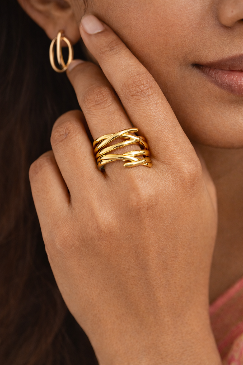Anti-Tarnish, Ashaarya, Ashaarya Jewels, Ashaarya Jewellery, Close-up of a hand wearing gold rings with an earring, on a neutral background