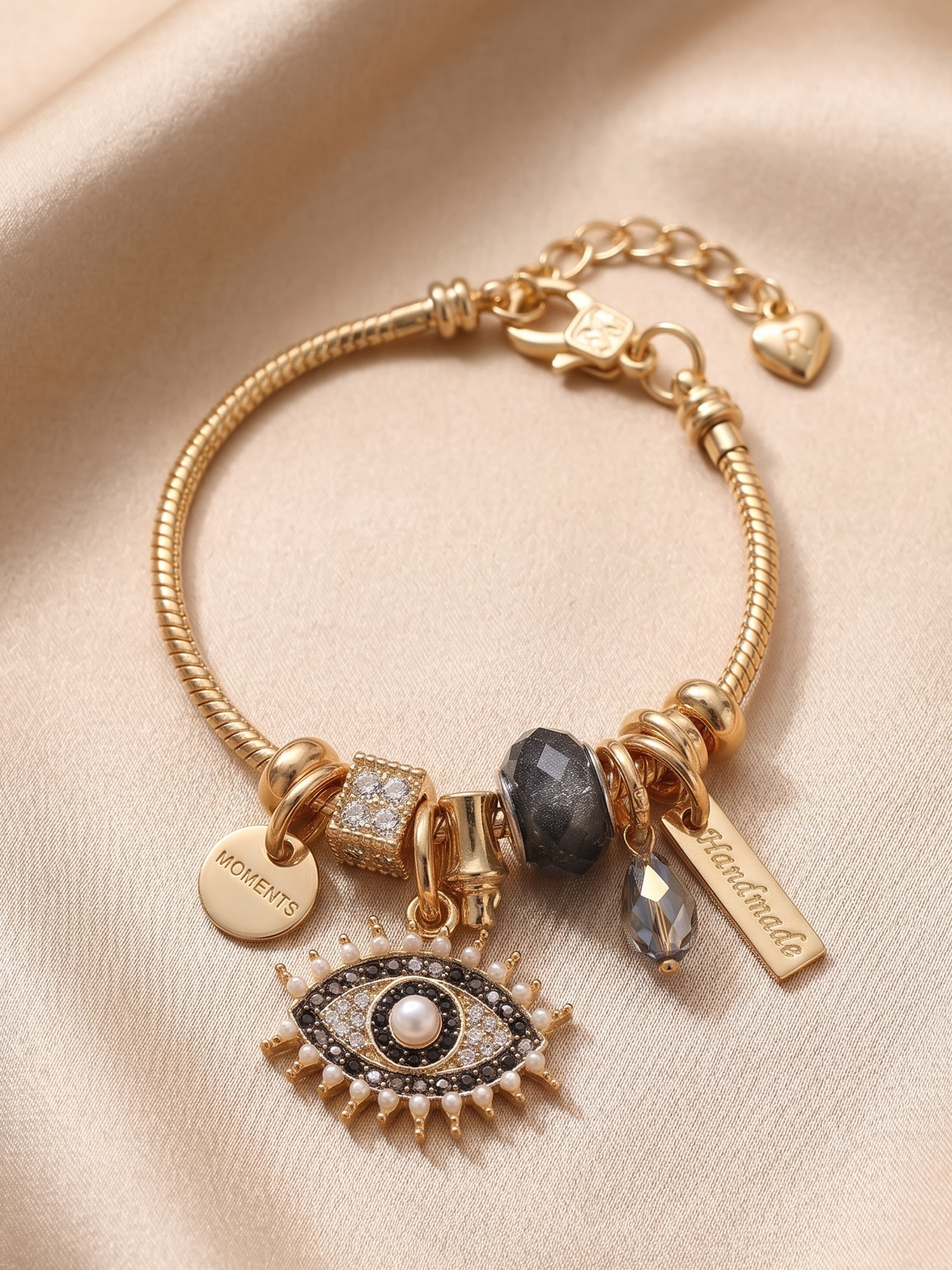 Detailed macro shot of Ashaarya Noor-E-Nazar charm bracelet with evil eye charm, textured beads and premium gold-tone finish.