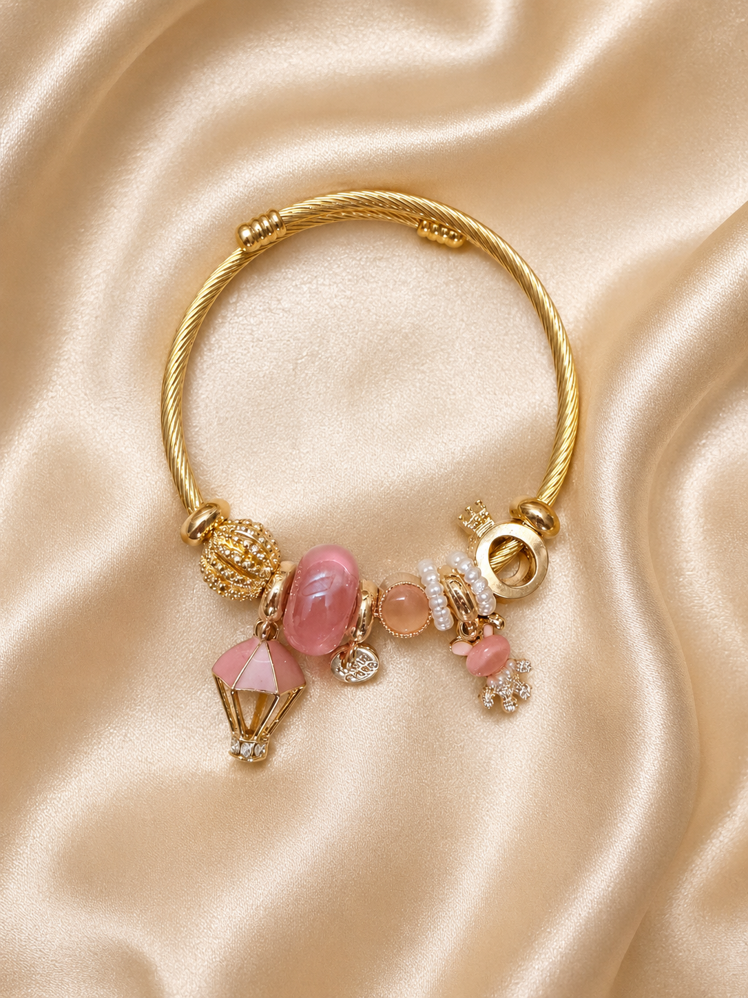 Close-up of blush pink charms, pearl details and crystal accents on Pink Postcards comfort jewellery bracelet