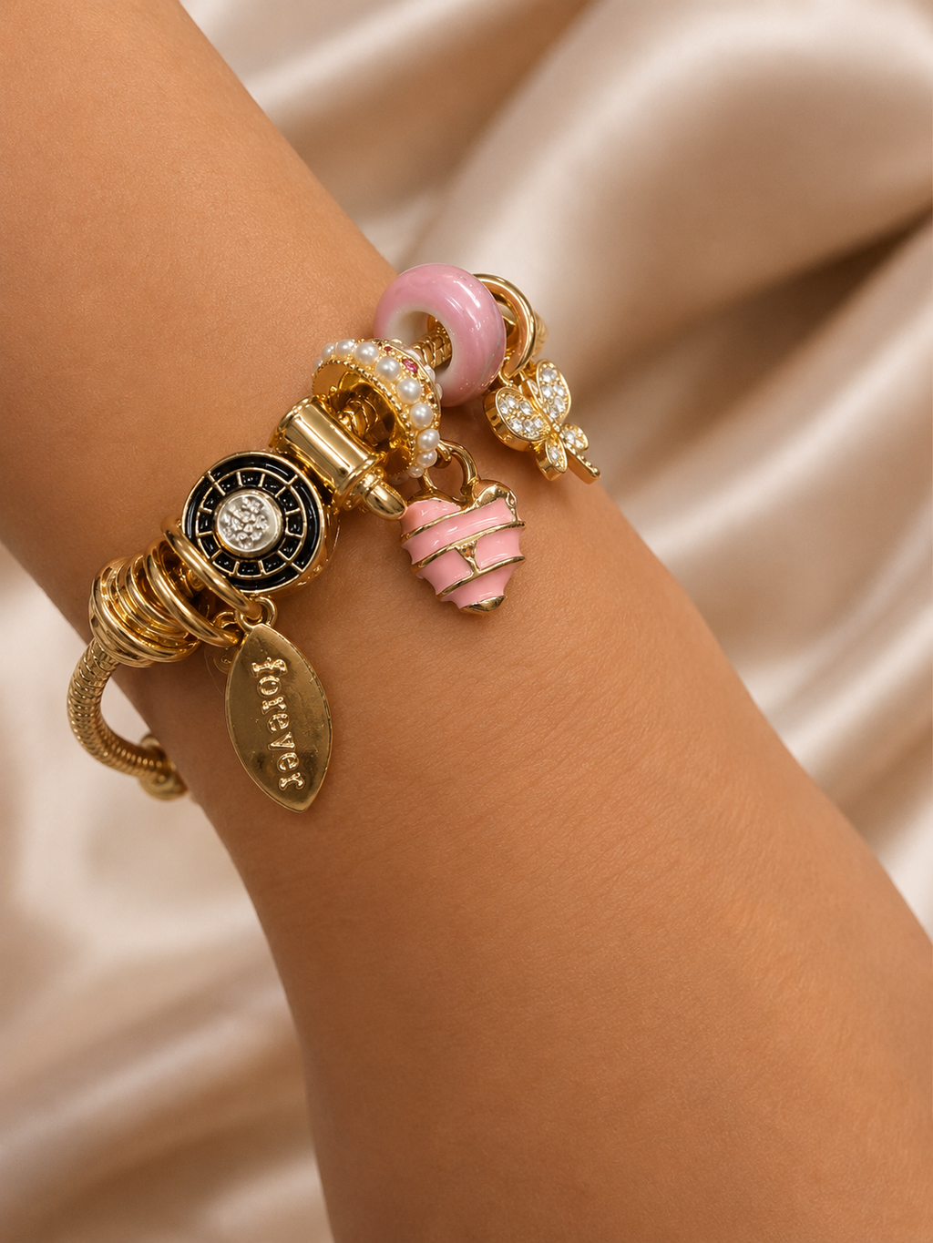 Model wearing Blush Forever Charm Bracelet by Ashaarya crafted in 316L stainless steel with an 18KT gold tone finish. charm bracelet, pink charm bracelet, heart charm bracelet, butterfly charm bracelet, gold charm bracelet for women, anti tarnish jewellery, 316L stainless steel jewellery, lightweight bracelet, skin friendly jewellery, adjustable bracelet, everyday bracelet, demi fine jewellery, comfort jewellery, luxury charm bracelet, Ashaarya charm bracelet