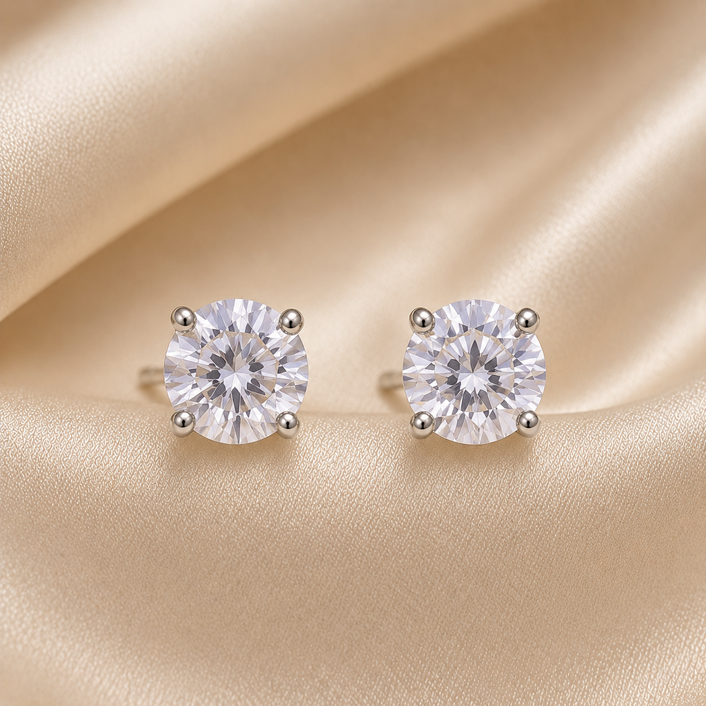 Pair of diamond stud earrings on a beige fabric background.royal trio earrings set, crown earrings for women, silver crown earrings, crown stud earrings, crown drop earrings, stud earrings for women, anti tarnish earrings, stainless steel earrings, lightweight earrings, skin friendly earrings, hypoallergenic earrings, cubic zirconia earrings, silver earrings for girls, everyday earrings, party wear earrings, elegant stud earrings, dainty earrings, premium earrings for women, earrings combo set, three pair e