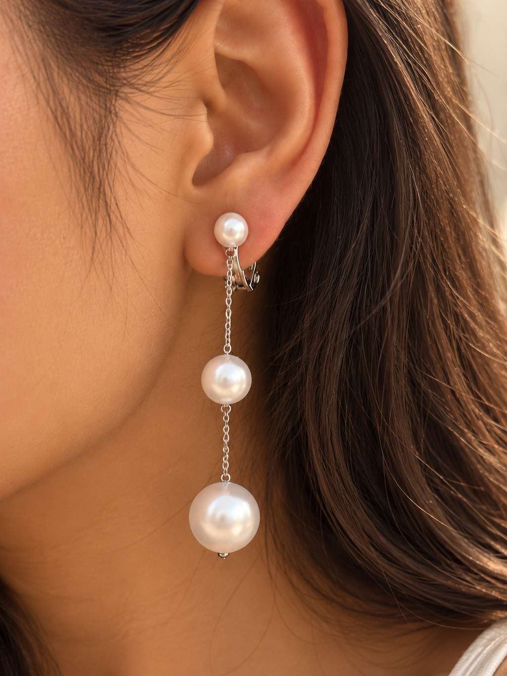 Elegant cascading pearl drop earrings displayed on a hand, showcasing their elongated design and lustrous white pearl accents.