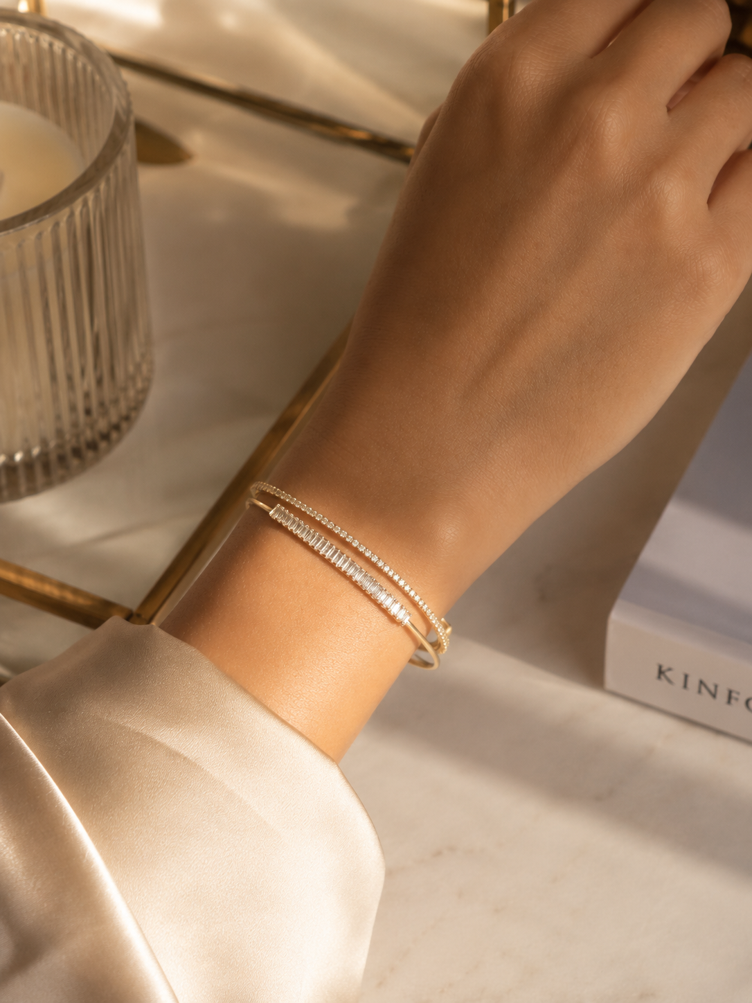 Gold bracelet for women with a modern open cuff design, featuring baguette-cut and round crystal detailing for a refined look
