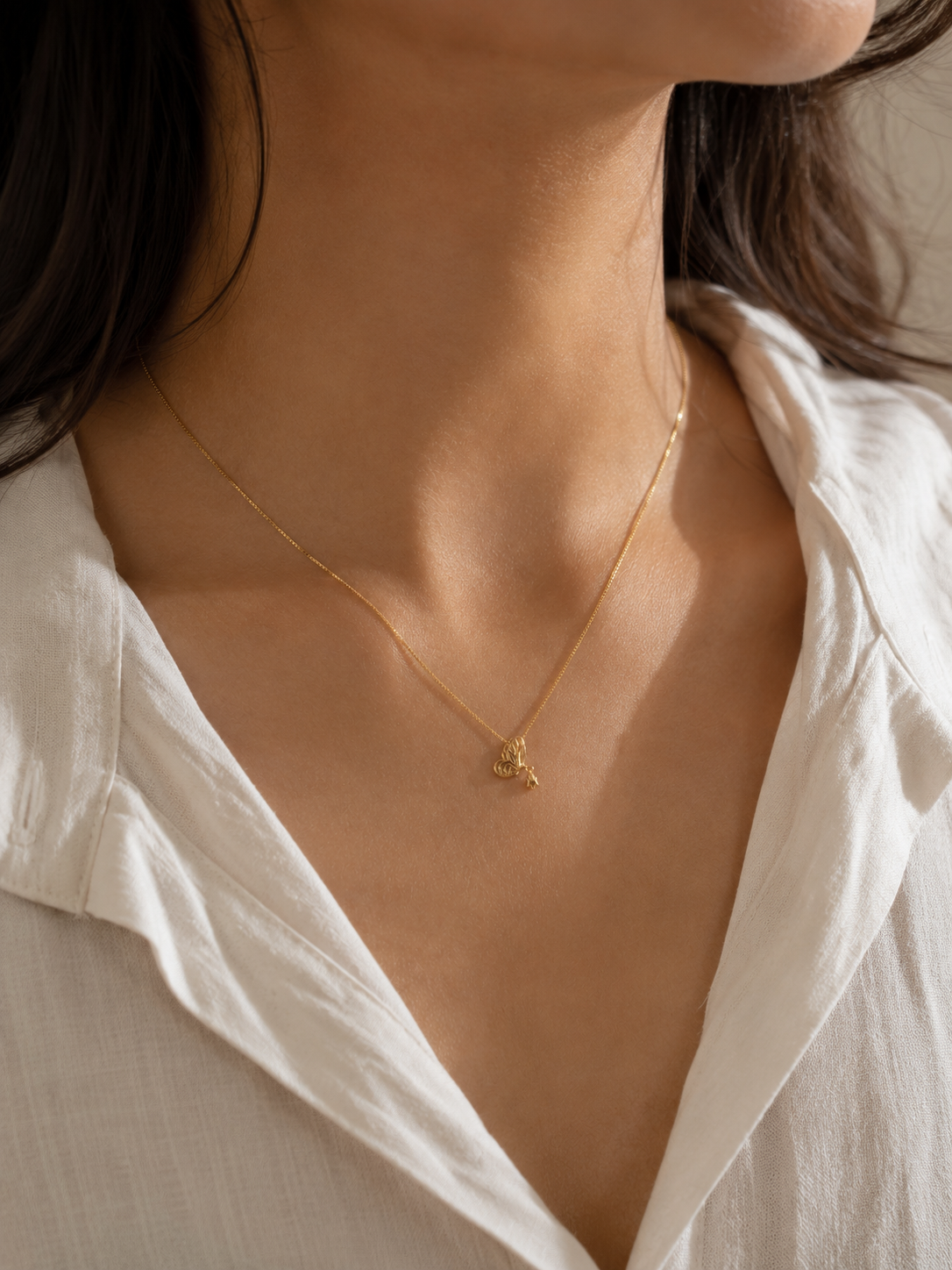 Close-up of Ashaarya's delicate gold butterfly pendant necklace showcasing the pendant design and fine chain.