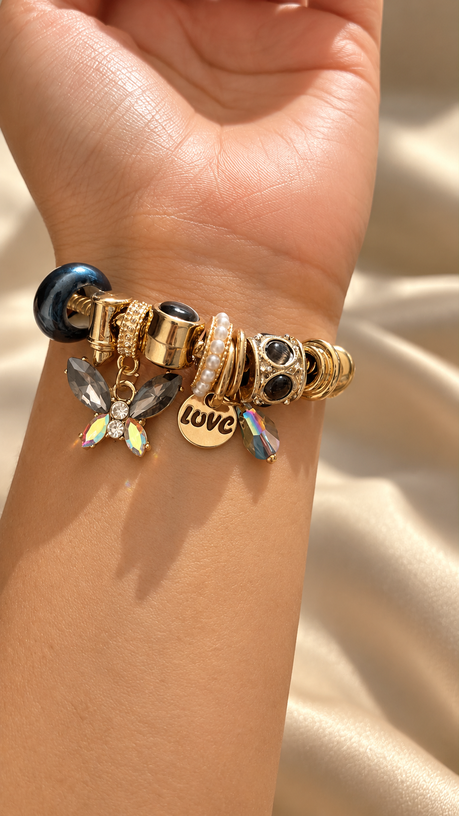 Close-up of Ashaarya anti-tarnish charm bracelet showcasing 9 intricate charms with dark stones, iridescent crystals, pearl accents and gold-tone details.