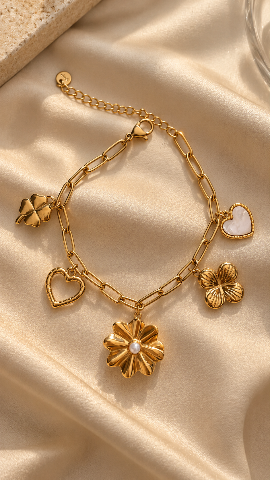 Gold-tone charm bracelet for women by Ashaarya featuring heart, flower, clover-inspired and pearl-detail charms on a paperclip chain.
Copy filename