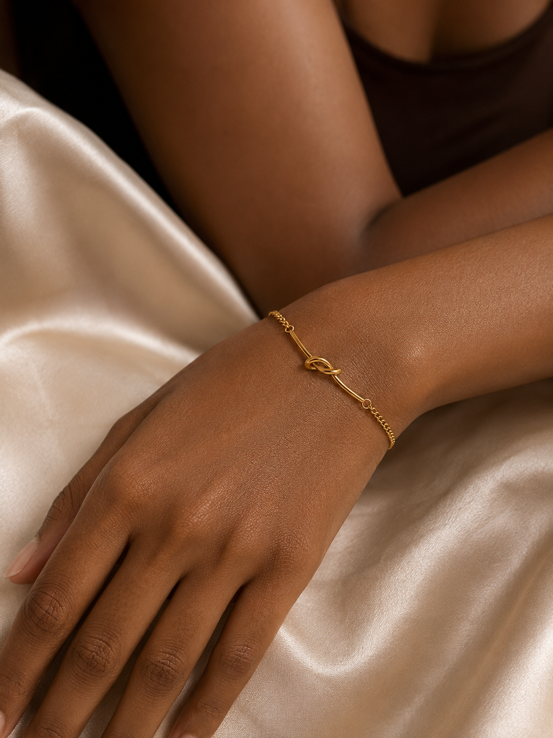 Dark-toned model wearing Ashaarya's anti-tarnish gold knot bracelet, highlighting the elegant minimalist design.
