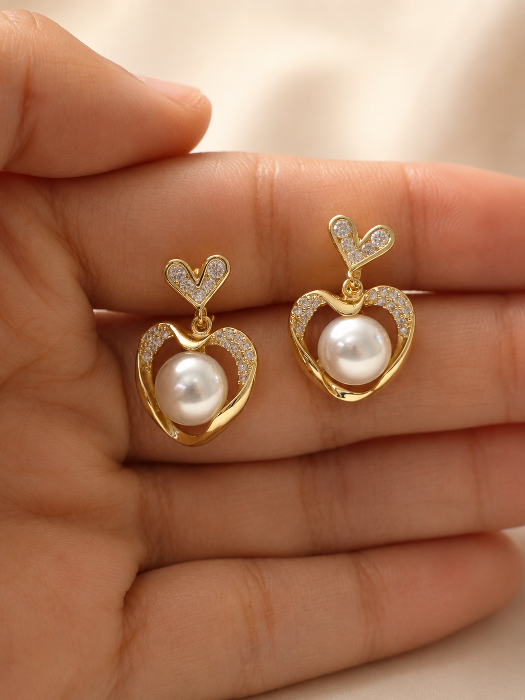 Gold pearl heart dangling earrings with a delicate heart-shaped design and luminous pearl centre