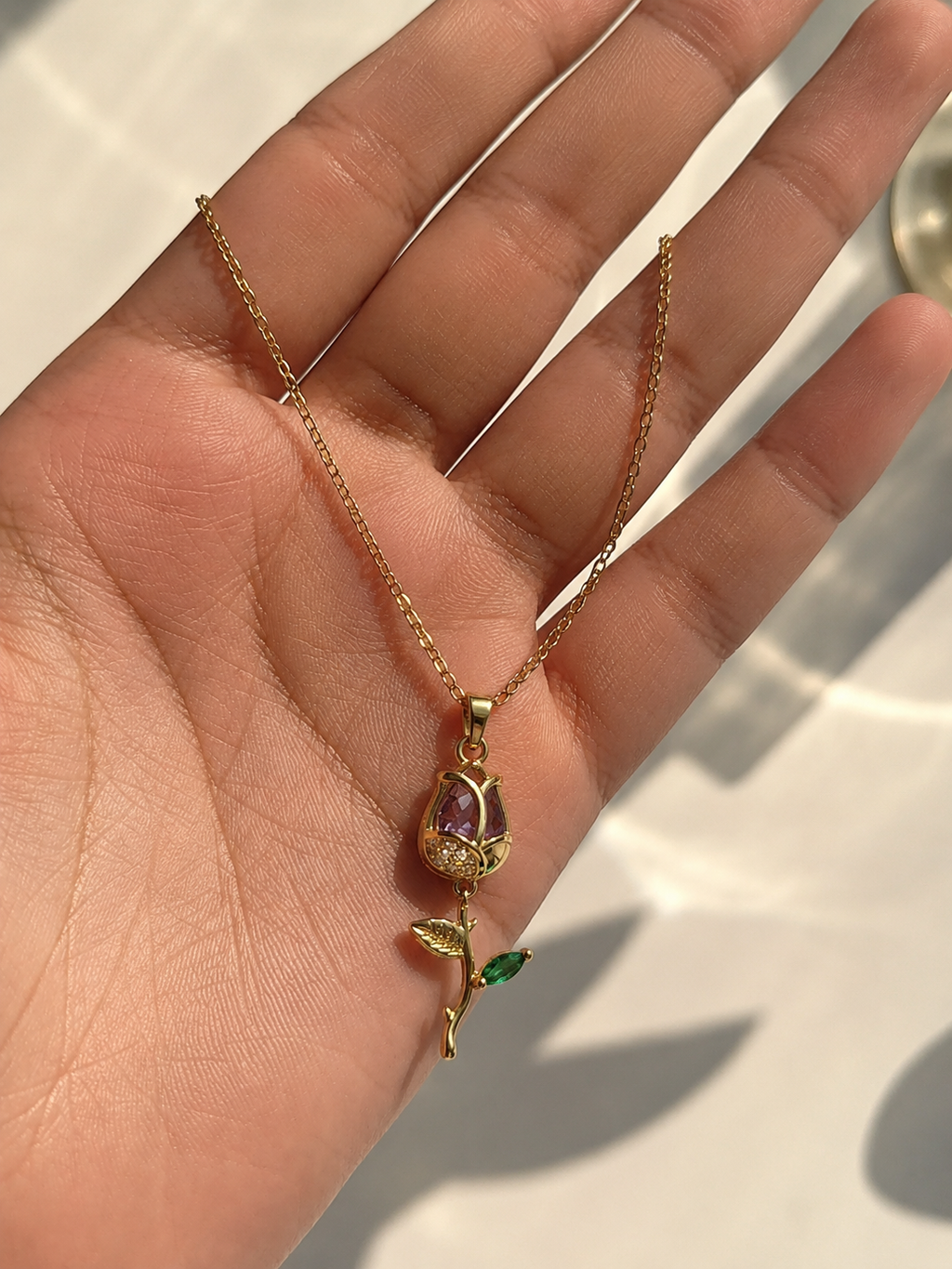 Gold purple and green stone necklace for women with a detailed botanical pendant and delicate chain design