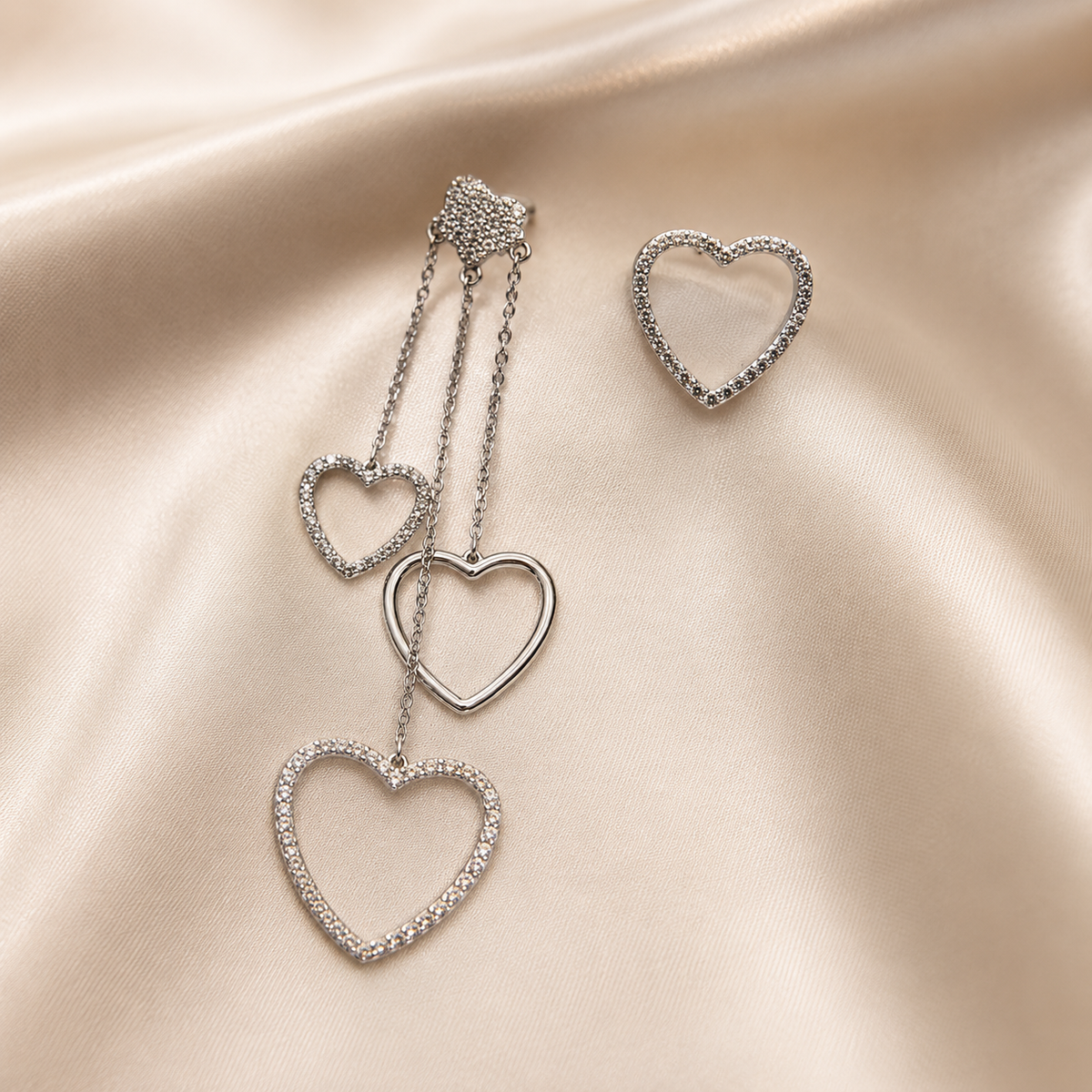 Silver heart-shaped necklace and ring on a satin surface. silver heart stud earrings, heart earrings for women, silver stud earrings, anti tarnish earrings, lightweight earrings, stainless steel earrings, skin friendly earrings, cubic zirconia earrings, everyday earrings, dainty heart earrings, comfort jewellery, Ashaarya