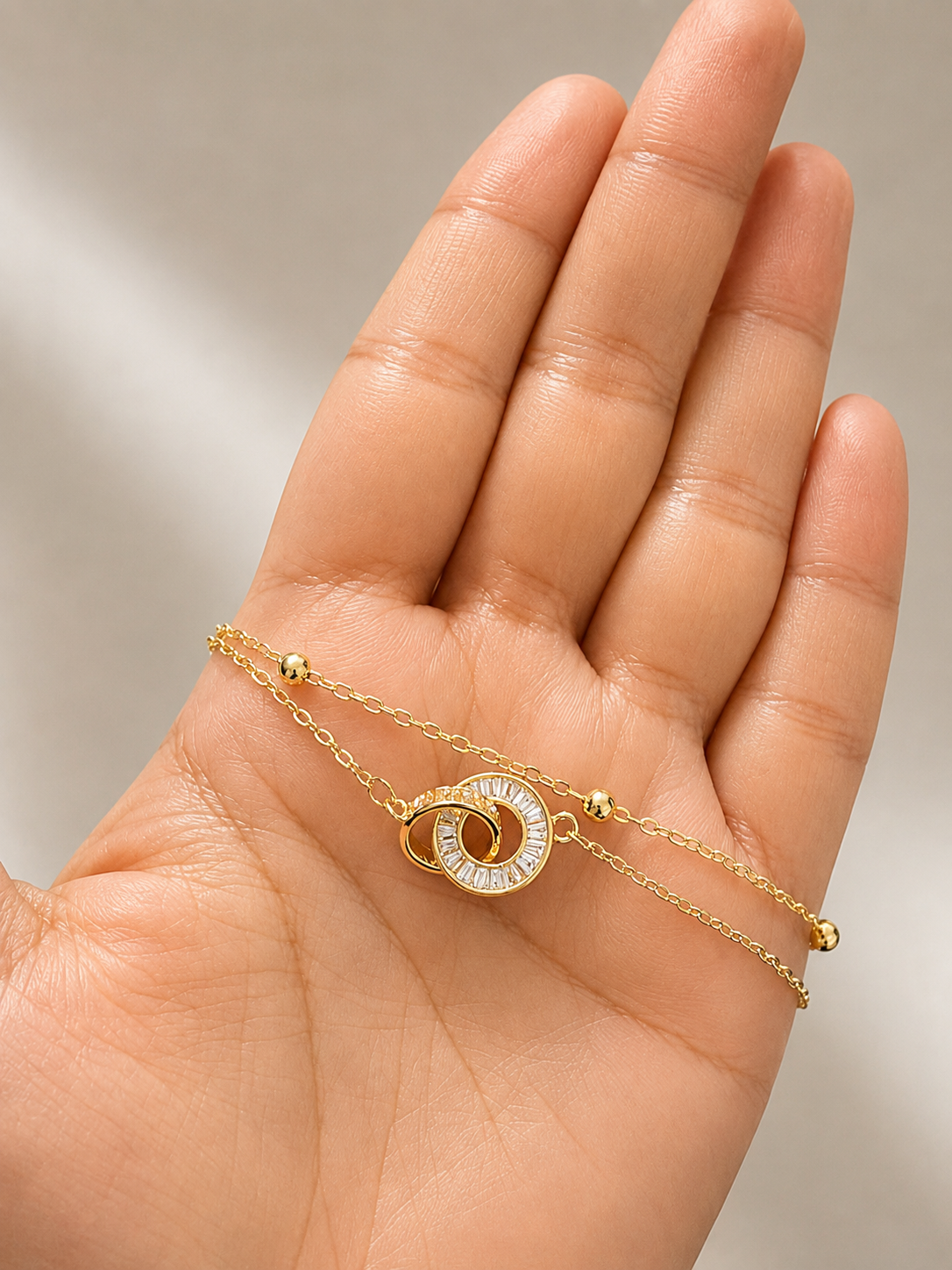 A delicate gold chain bracelet with a spiral sunburst charm, displayed on an open hand against a soft, neutral background. lightweight-comfort-jewellery-bracelet-for-women