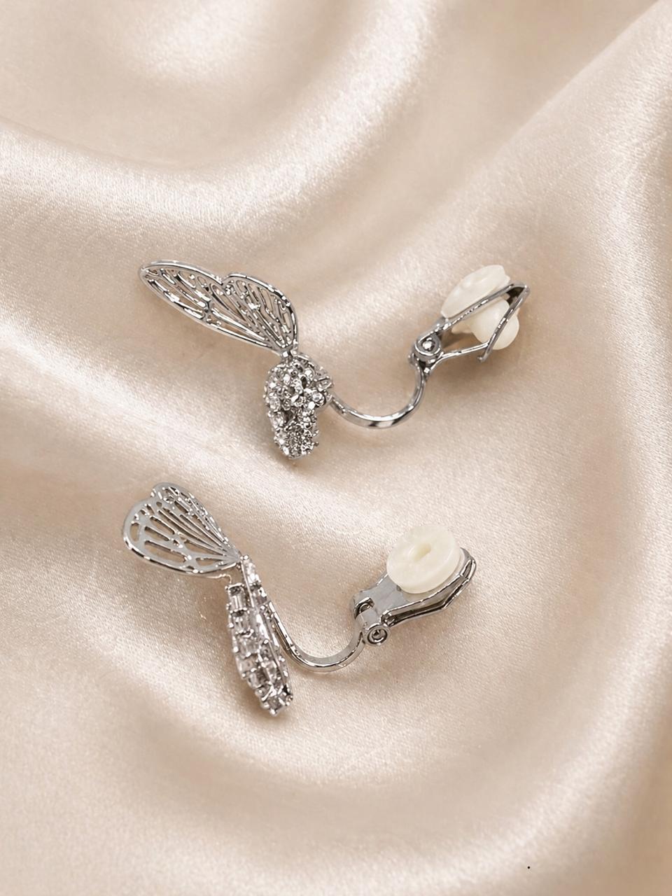 Lightweight statement dangling earrings for women with sculptural wing design, anti-tarnish comfort jewellery. Silver earrings with gemstones on a beige fabric background