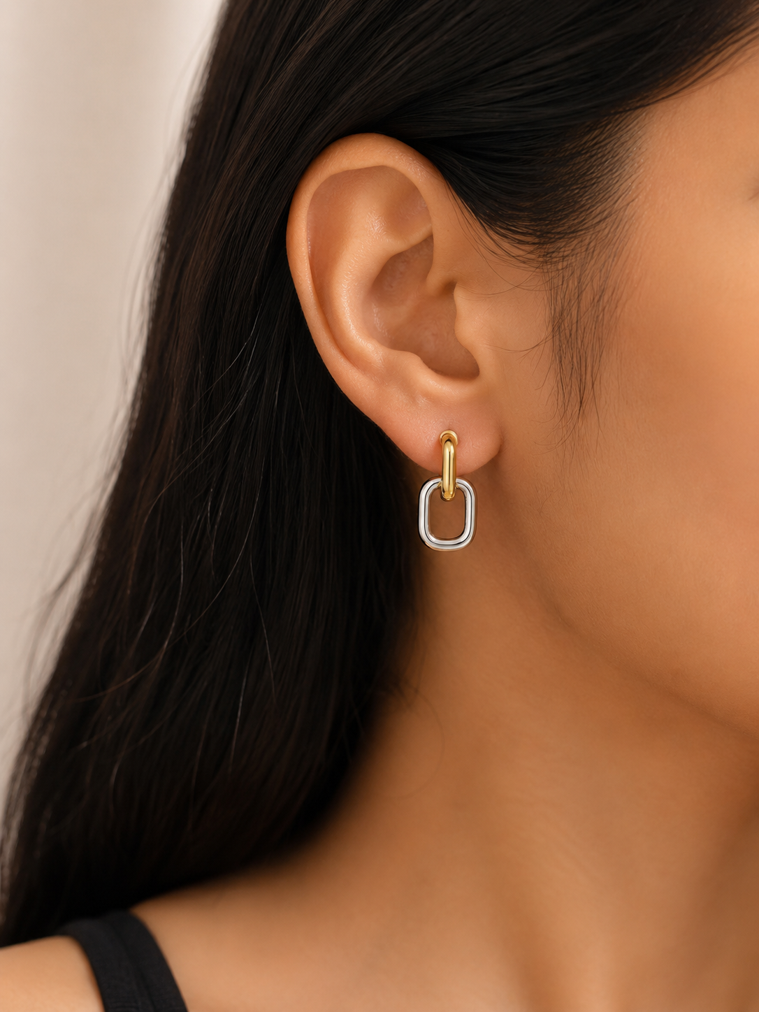 Close-up of an ear wearing a gold and silver hoop earring against a neutral background. two tone earrings, gold and silver earrings, stainless steel earrings, anti tarnish earrings, lightweight earrings, statement earrings for women, geometric earrings, modern earrings, link earrings, everyday earrings, skin friendly jewellery, comfort jewellery