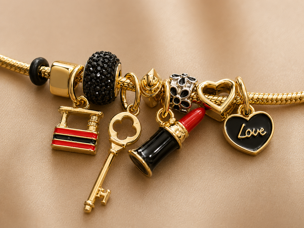 Close-up of fashion-inspired charm bracelet with black crystal bead and gold-tone charms