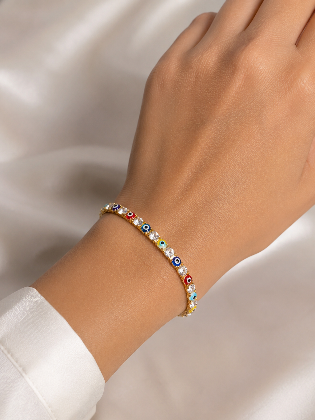 Close-up of multicoloured evil eye motifs and American diamond detailing on Ashaarya's gold-tone bracelet.