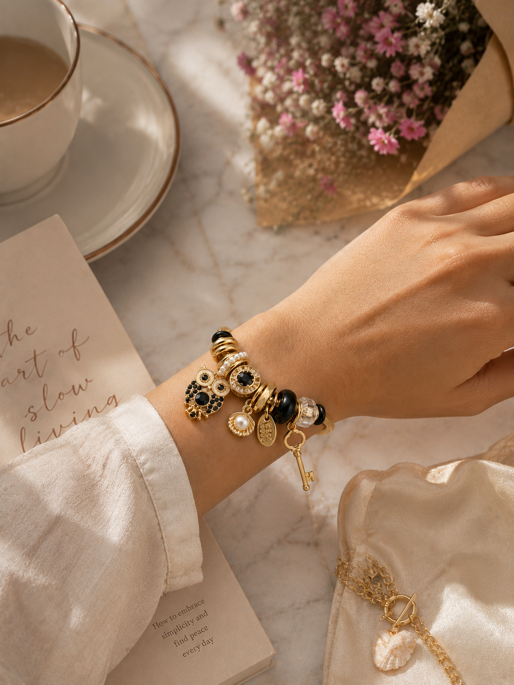 Woman holding the Noir Wisdom Charm Bracelet by Ashaarya with black and gold symbolic charms.