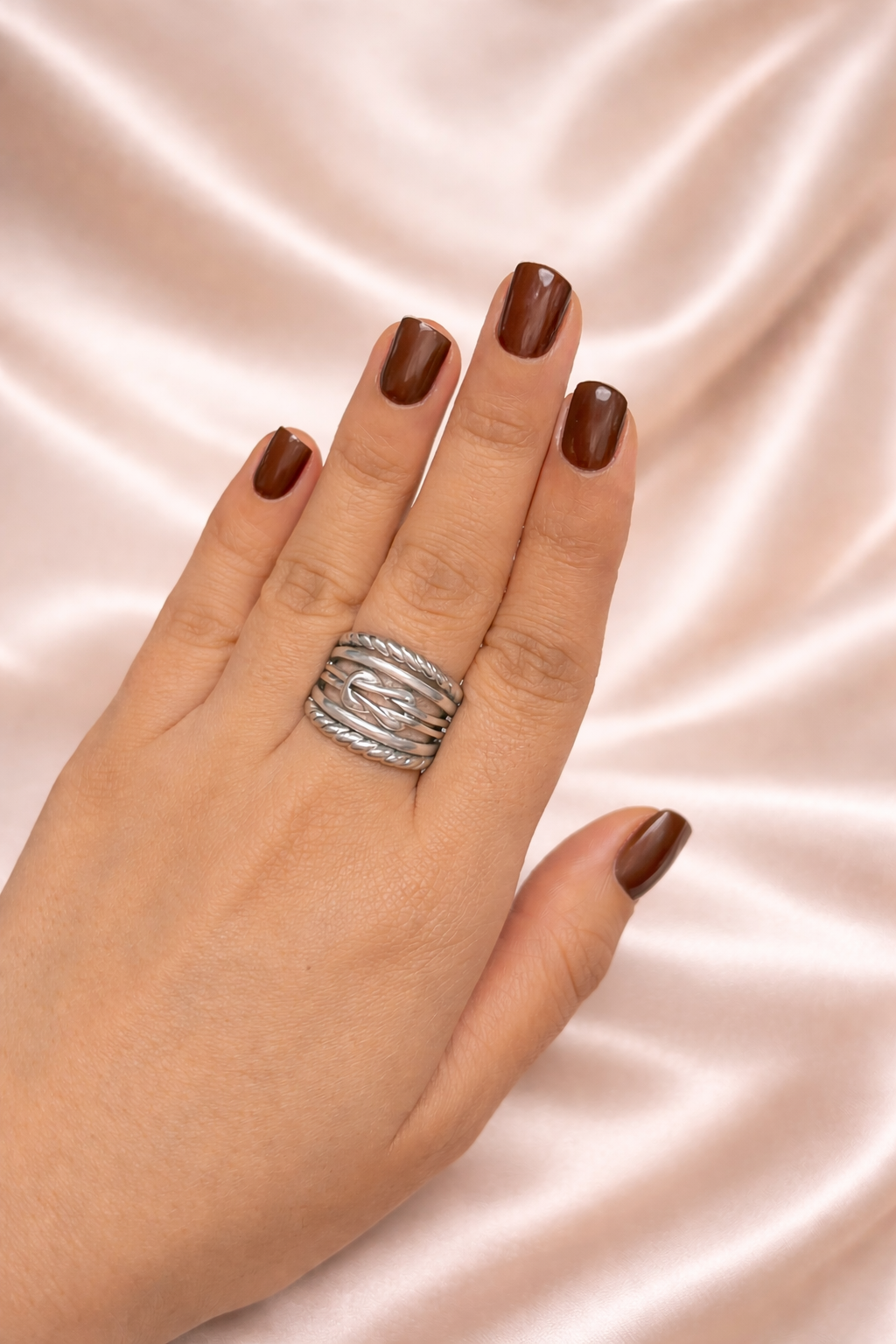 Noor Jaal anti-tarnish statement ring adjustable silver band rings for women comfort jewellery statement rings for women Ashaarya Hand wearing a silver ring with dark nail polish on a pink satin background
