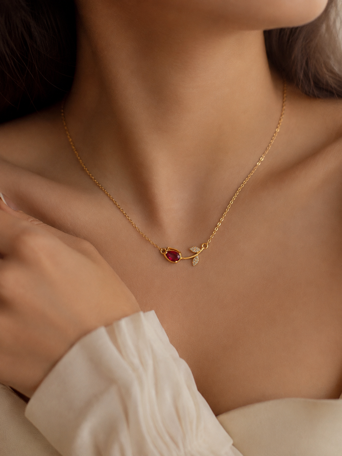 Red stone gold necklace for women with a delicate chain, ruby-toned gemstone and elegant crystal leaf detailing