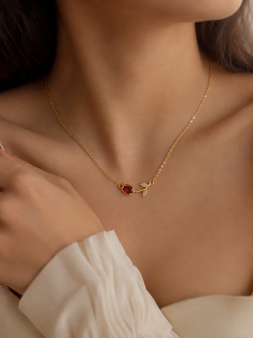 Red stone gold necklace for women with a delicate chain, ruby-toned gemstone and elegant crystal leaf detailing