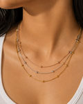 Close-up of a woman wearing a delicate gold necklace with small beads.trio necklace for women, layered necklace, tri colour necklace, three tone necklace, stainless steel necklace, anti tarnish necklace, lightweight necklace, everyday necklace, luxury necklace for women, 18KT gold plated necklace, rose gold necklace, silver necklace, beaded necklace, demi fine jewellery, comfort jewellery, Ashaarya necklace